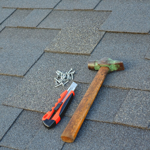 asphalt bitumen shingles on a roof  with hammer and nails 